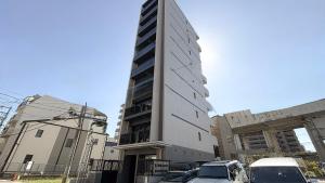 福岡市にあるLiving like hotel Hakata Premiumの前に車が駐車されている高い建物