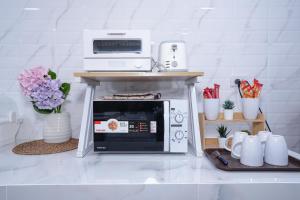 a microwave sitting on top of a table with cups at Cozy KingsizeBed เจริญนคร in Ban Hua Phrong