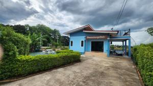 Un pequeño edificio azul con un patio al frente. en บ้านกลางนาพูลวิลล่า, en Nan