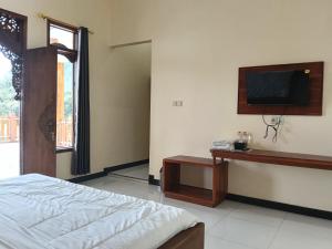 a bedroom with a bed and a tv on the wall at Km 31 Sujono Guesthouse in Bromo
