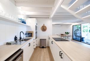 a kitchen with white cabinets and a large window at The Rest Family Cottage with Resort Style Pool in Noosa Heads