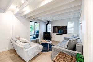 a living room with two couches and a tv at The Rest Family Cottage with Resort Style Pool in Noosa Heads
