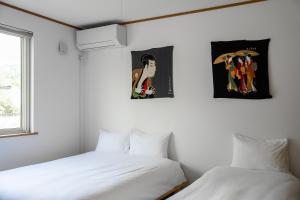 2 Betten in einem Zimmer mit Plakaten an der Wand in der Unterkunft Toya Serenity Stay in Tōya-See + 172 Fotos