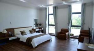 a bedroom with a bed and a couch and windows at Hoang Hung Hotel in Hanoi