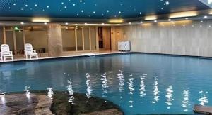 a large swimming pool with chairs in a building at Grand Metropark Hotel Qingdao in Qingdao