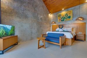 a bedroom with a bed with a blue chair and a tv at Sweet Escape 1BR Matahari LaLuxe A22 Sanur Villa in Sanur