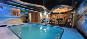 a swimming pool with an umbrella and a table at Pousada Primeiro Sol in João Pessoa