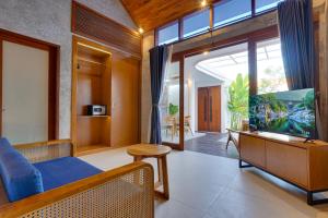 a living room with a blue couch and a tv at Sweet Escape 1BR Matahari LaLuxe A22 Sanur Villa in Sanur