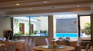 a room with tables and white chairs and a swimming pool at Grand Hotel Surabaya in Surabaya