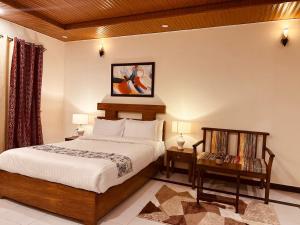 a bedroom with a bed and two tables and a painting at Nook House - Valley View Villa in Murree