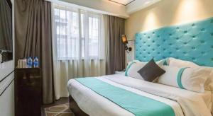 a bedroom with a large bed with a blue headboard at Xana Lite Beijing Sidaokou Dazhong Temple Metro Station Branch in Beijing +120 photos