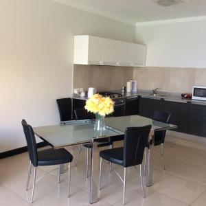 una mesa de comedor con sillas y un jarrón de flores. en Mobydick Apartments by RBG, en Xlendi