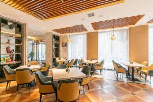 Un restaurante con mesas, sillas y ventanas. en Jinjiang Metropolo Zhengzhou Songshan Road, en Zhengzhou