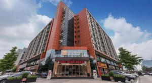 a tall red building with cars parked in front of it at James Joyce Coffetel·Beijing Yizhuang Development Zone Dazu Square Tongji Road in Beijing