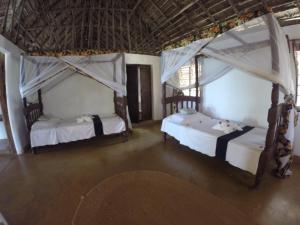 two beds in a room with two canopy beds at Che Che Vule by SeVi Exclusive Beach Villa in Matemwe