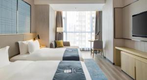 a hotel room with two beds and a flat screen tv at Echarm Hotel Changsha Gaoqiao in Changsha