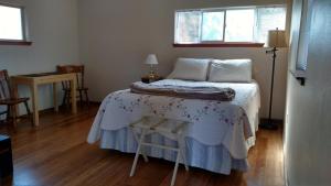 a bedroom with a bed with a table and two windows at Jones Cabin in Friday Harbor