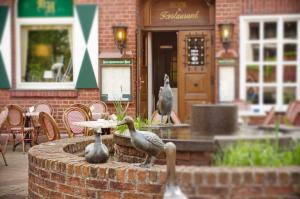 two birds standing on a fountain in front of a building at Hotel Restaurant Knechtstedener Hof in Dormagen