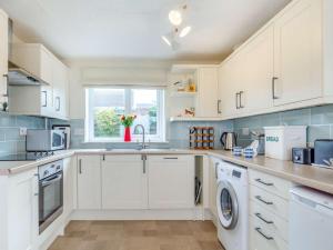 a kitchen with white cabinets and a sink at 3 Bed in Porthtowan 90556 in Porthtowan +12 photos