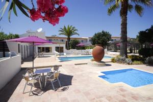 een patio met een tafel en stoelen en een zwembad bij Centre Algarve in Moncarapacho