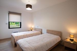 a bedroom with two beds and a window and two lamps at Entre genêts et chardons in Banassac