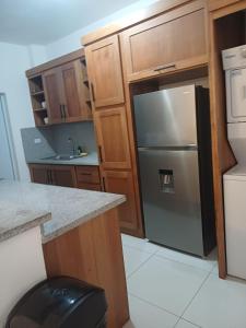 a kitchen with a stainless steel refrigerator and wooden cabinets at Sunrise Apartments in San Felipe de Puerto Plata +15 photos
