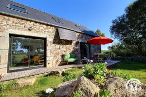 een stenen huis met een terras met een rode parasol bij Rumedon in Ploumilliau