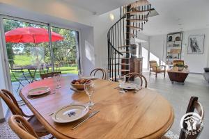 een eetkamer met een houten tafel en een rode parasol bij Rumedon in Ploumilliau