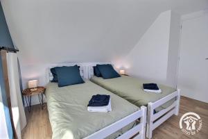 2 bedden in een kleine kamer met blauwe kussens bij Rumedon in Ploumilliau