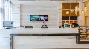 a woman sitting at a counter in an office at City Comfort Inn Chengdu Southwest University of Finance and Economics Wansheng Metro Station in Chengdu