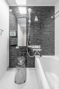 a bathroom with a shower and a tub and a mirror at Akatsuki in Kami-furano