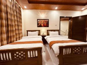 two beds in a hotel room with at Nook House - Valley View Villa in Murree