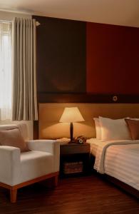 a bedroom with a bed and a chair and a lamp at Asian Ruby Hotel & Spa - 122F Bui Thi Xuân Street in Ho Chi Minh City
