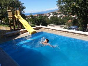 a person swimming in a swimming pool with a slide at BC Bikers Welcome Apartments in Senj