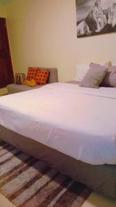 een groot wit bed in een kamer met een bank bij Home sweet Home in Entebbe