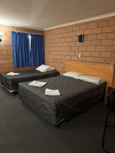 two beds in a room with blue curtains at The Lodge Village & Motel, Moranbah in Moranbah