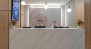 two women sitting at a counter with their laptops at Shell Hotel Shnaghai Beiqiao Metro Station in Shanghai