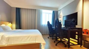 a hotel room with a bed and a desk with a computer at VX Hotel Wuhan Optics Valley Yangjia Bay Metro Station in Wuhan