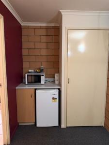 a small kitchen with a microwave and a refrigerator at The Lodge Village & Motel, Moranbah in Moranbah