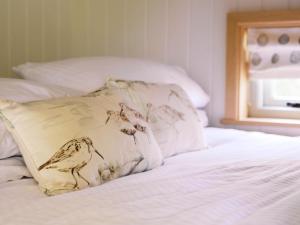 a pillow with birds on it sitting on a bed at Herbie's Shepherds Hut at Shepherds Lodge Retreat and Wellness in Nottingham