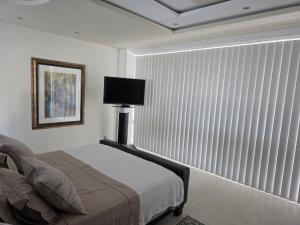 a bedroom with a bed and a large window with vertical blinds at Amigos para Sempre - Guesthouse in Ferragudo