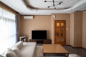 a living room with a white couch and a tv at Kamifurano House in Kami-furano