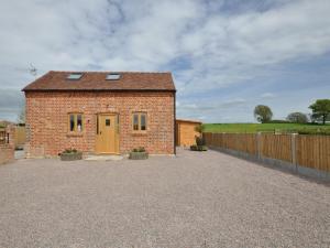 ein Backsteinhaus mit einer gelben Tür auf einer Kiesauffahrt in der Unterkunft 1 Bed in Cheltenham 60276 in Tirley