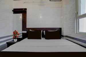 a bedroom with a large white bed with a window at Super Hotel O Krishna Janam Bhoomi Formerly Ashirwad Palace in Mathura