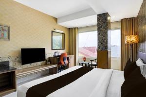 a hotel room with a bed and a television at Super Townhouse Oak ONGC Crossway Formerly Hotel Gold Stone Comfort in Dehradun