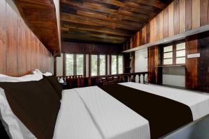 a bedroom with a large bed with wooden walls and windows at Super Collection O Chalakkudy River Annamanada Formerly Svasthya Retreat in Māla +30 photos