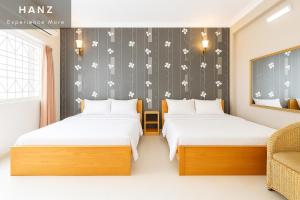 a bedroom with two beds and a wall with flowers at S79 Bao Khoi Hotel in Vung Tau
