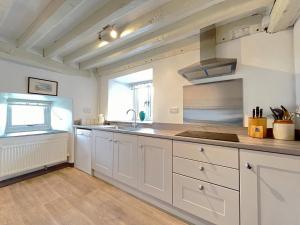 a kitchen with white cabinets and a sink and a window at 4 Bed in Betws y coed 52111 in Capel Garmon