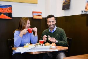 a man and woman sitting at a table drinking coffee at Hotel Sandmanns am Dom in Cologne