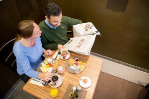 a man and a woman sitting at a table with food at Hotel Sandmanns am Dom in Cologne